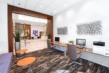 A modern office with a purple sofa and a wooden desk at Two Twelve Clayton Apartments, Clayton, Missouri